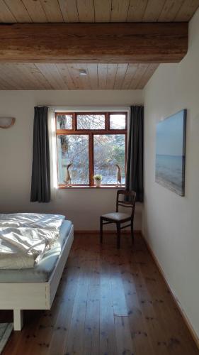 a bedroom with a bed and a chair and a window at FeWo Strohbrück in Quarnbek