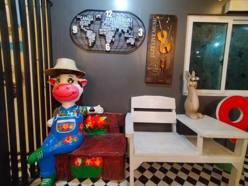 a statue of a cow wearing a hat next to a chair at Ruenthip Homestay in Bangkok