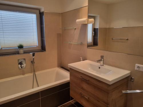 La salle de bains est pourvue d'un lavabo, d'une baignoire et d'un miroir. dans l'établissement Apartment Konrad, à Umhausen