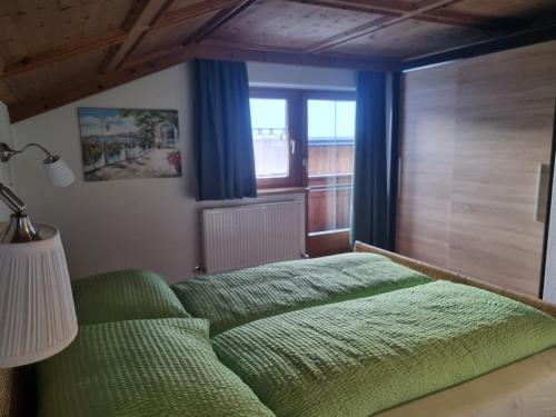 - une chambre avec un lit vert et une fenêtre dans l'établissement Apartment Konrad, à Umhausen