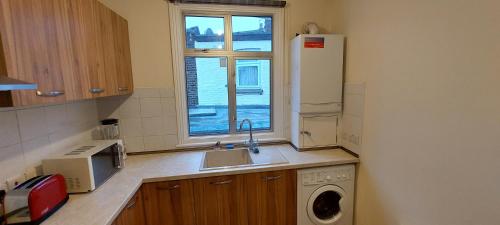 a kitchen with a sink and a refrigerator and a window at Family friendly 3 Bedroom Flat Zone 2 - children stay free! in London