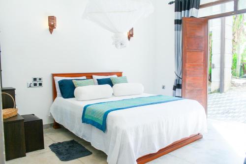 a white bedroom with a bed with blue pillows at Villa Freiheit Himmel in Bentota