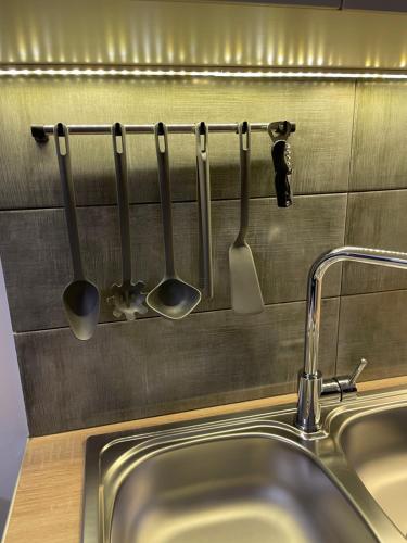 a row of utensils hanging on a wall above a sink at acropolis super cosy apartment in Athens