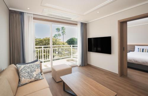 uma sala de estar com uma cama e uma grande janela em Kensington Resort Seogwipo em Seogwipo