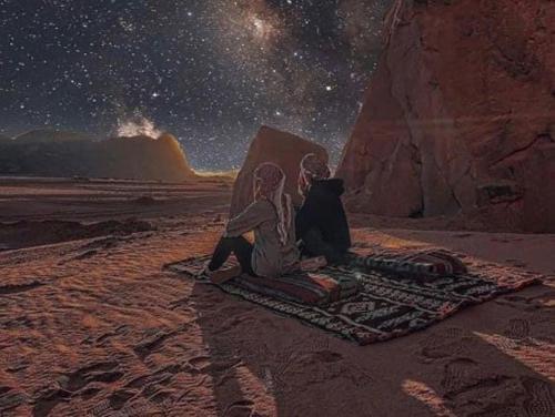 a couple sitting on the desert under the stars at Sand Star Camp in Wadi Rum