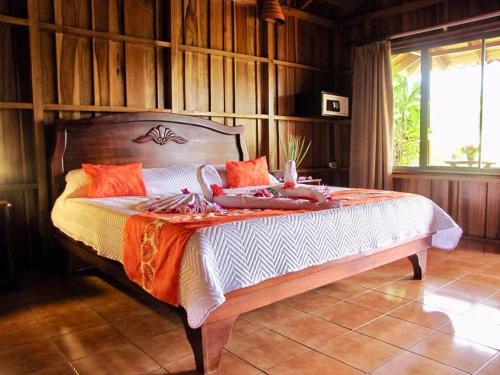 a bedroom with a large bed with an orange blanket at Hotel La Pradera del Arenal in Fortuna