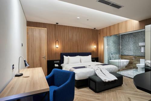 a bedroom with a bed and a bathroom with a tub at Cordela Suites Tasikmalaya in Tasikmalaya