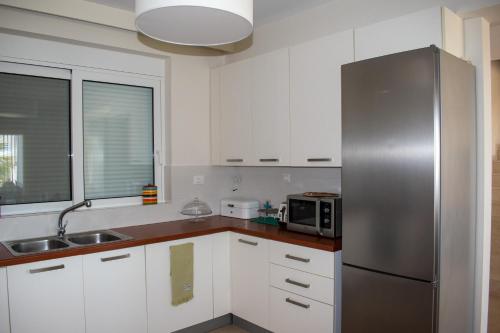 a kitchen with white cabinets and a stainless steel refrigerator at Greek Villas Justine View Beach in Kyllini