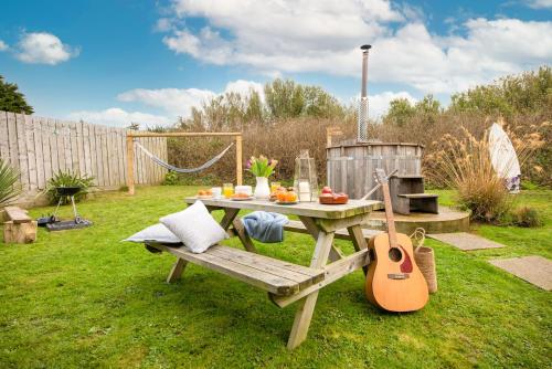 a picnic table and a guitar in a garden at Wheal Prosper- Beautifully Fitted Wooden Lodge Helston Cornwall in Helston