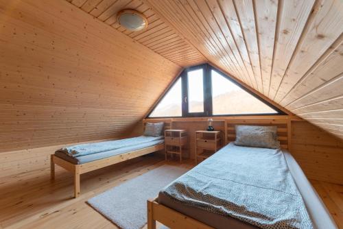 two beds in a room with a wooden ceiling at Farkaskútvölgy in Felsőtold
