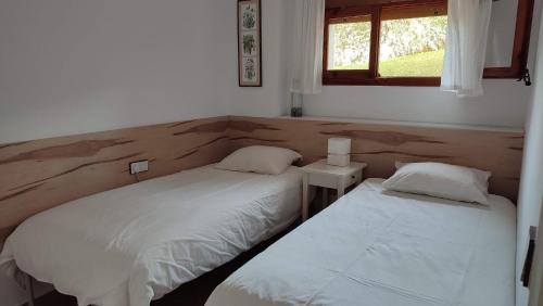2 Betten in einem kleinen Schlafzimmer mit Fenster in der Unterkunft Apartamento Ca la Raquel Calella Palafrugell in Calella de Palafrugell
