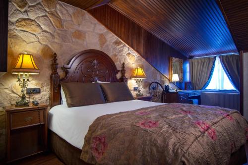 1 dormitorio con 1 cama grande y pared de piedra en Hotel Kassaros en Metsovo
