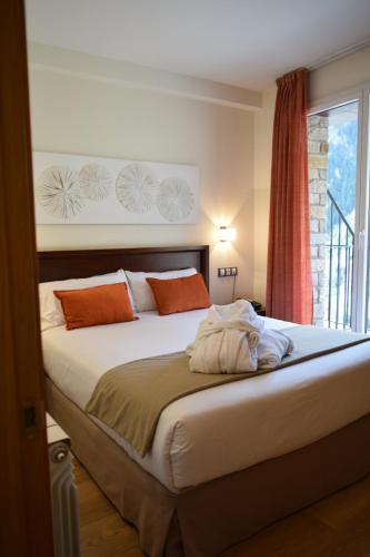 Un dormitorio con una cama con almohadas naranjas y una ventana. en Obaga Blanca & Spa, en Canillo
