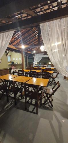 a dining room with wooden tables and chairs and curtains at Pousada Sakura Rio Mar in Abraão