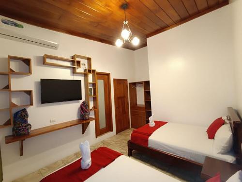 a bedroom with a bed and a flat screen tv at El Arco de Darwin in Puerto Ayora