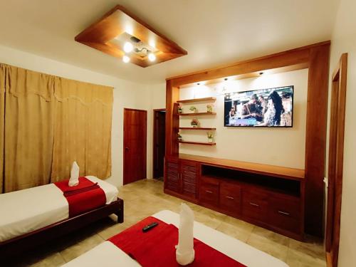 um quarto com duas camas e uma televisão na parede em El Arco de Darwin em Puerto Ayora
