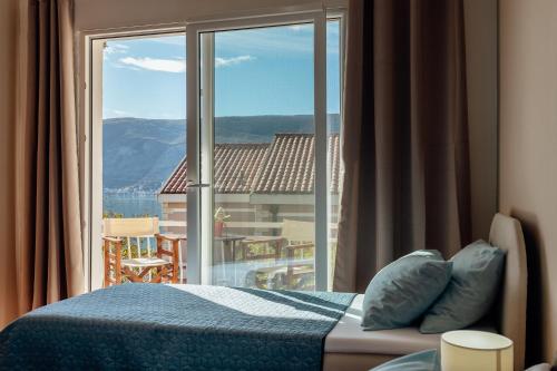 sypialnia z łóżkiem i dużym oknem w obiekcie Apartmani Vico w mieście Herceg Novi