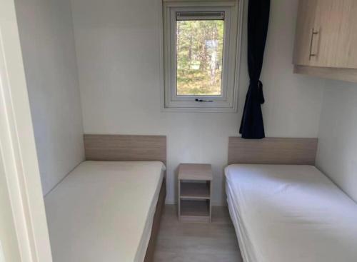 a small room with two beds and a window at Ibiza huisje in Den Hoorn