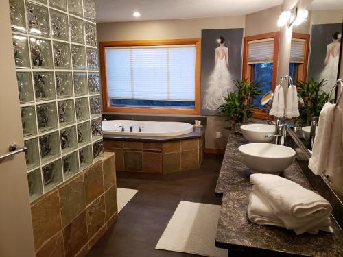 La salle de bains est pourvue de 2 lavabos, d'une baignoire et d'une fenêtre. dans l'établissement South Africa House Guest Lodge, à Wainwright