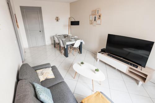 salon z kanapą, telewizorem i stołem w obiekcie Le Neptune Apt 85m2 3ch Appart Hotel Poitiers w mieście Poitiers