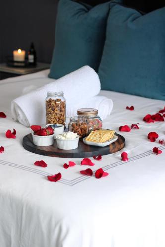 a tray of food on a bed with red flowers at The Raz in Harrismith