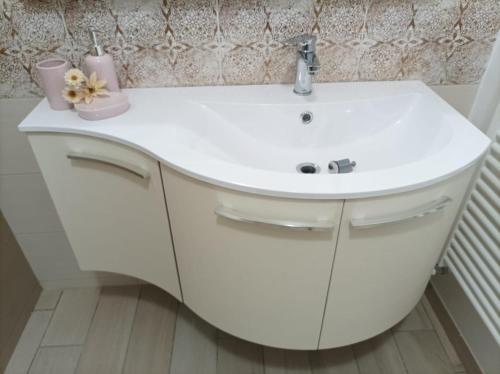 a white bathroom sink with two candles and flowers on it at Sweet Home Annalisa in Ortona