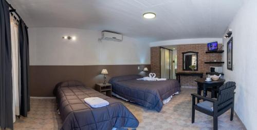 ein Hotelzimmer mit zwei Betten und einem Fernseher in der Unterkunft Hotel La Colina del Sol in Villa Carlos Paz