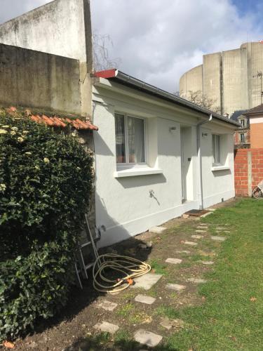 een wit huis met een raam en een heg bij Maisonnette de charme au calme près des bords de Marnes in Saint-Maur-des-Fossés