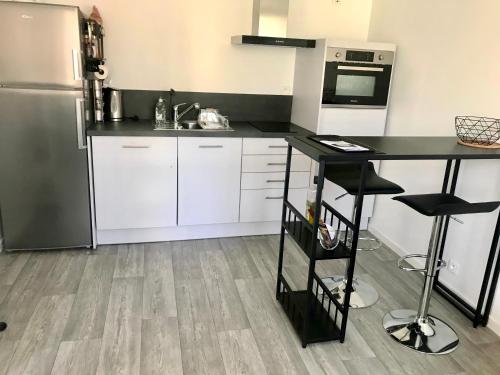 une cuisine avec des armoires blanches et un comptoir noir dans l'établissement Maisonnette de charme au calme près des bords de Marnes, à Saint-Maur-des-Fossés