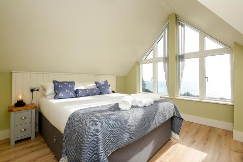 een slaapkamer met een bed met blauwe kussens en een raam bij Fishermans Heights in Polperro
