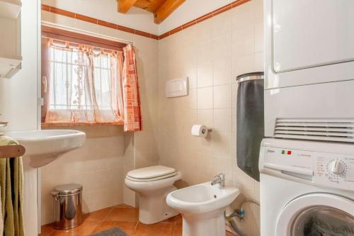 a bathroom with a toilet and a sink and a washing machine at La casetta nel borgo in Pescantina