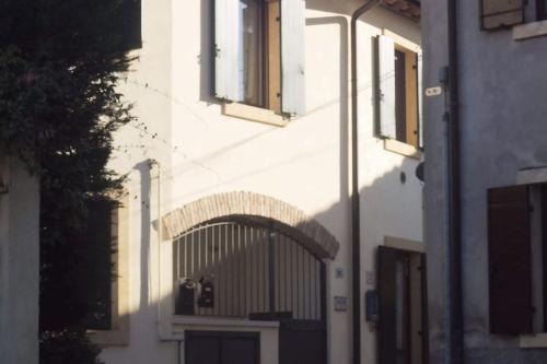 a white building with a gate and windows at La casetta nel borgo in Pescantina