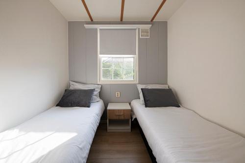 2 łóżka w małym pokoju z oknem w obiekcie 89, Groenvink - one with nature! w mieście Oisterwijk