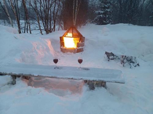 a table with two wine glasses and a lantern in the snow at Le Relais de la Martine in Petite-Rivière-Saint-François