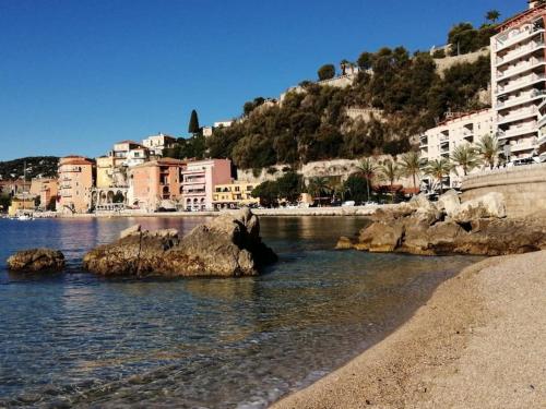 a view of a beach with buildings on a hill at appartement cosy situé à 2mn de la plage à pied climatise in Villefranche-sur-Mer