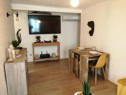 sala de estar con mesa y TV en la pared en appartement cosy situé à 2mn de la plage à pied climatise, en Villefranche-sur-Mer