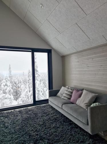 a living room with a couch and a large window at Huvila Hukanhuippu in Syöte