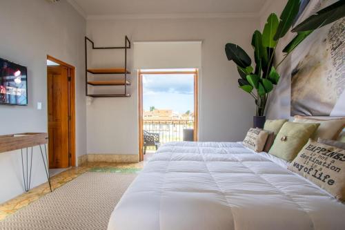 een groot wit bed in een kamer met een raam bij AmazINN Places Casco Viejo Pool and Rooftop XIV in Panama-Stad