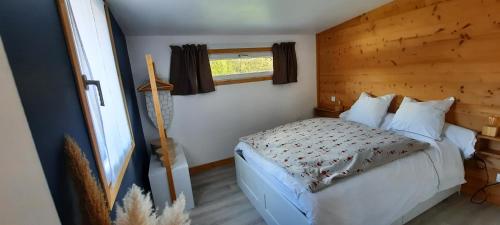a bedroom with a bed with a wooden wall at Studio au pied des montagnes in Le Bourg-dʼOisans