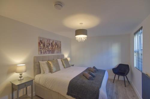 a bedroom with a bed and a chair and a window at Marina Walk, New Luxury Coastal Apartment in The English Riviera, close to the Shops, Bars and Restaurants with Torquay Marina and Torre Abbey Sands Beach a short walk away! in Torquay