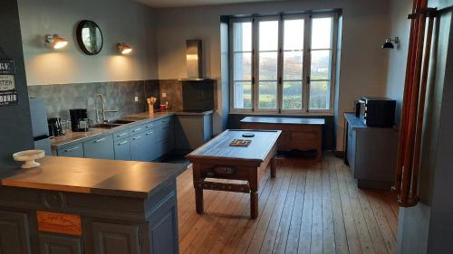 eine große Küche mit blauen Schränken und einem großen Fenster in der Unterkunft Les Mancelles in Condé-sur-Sarthe