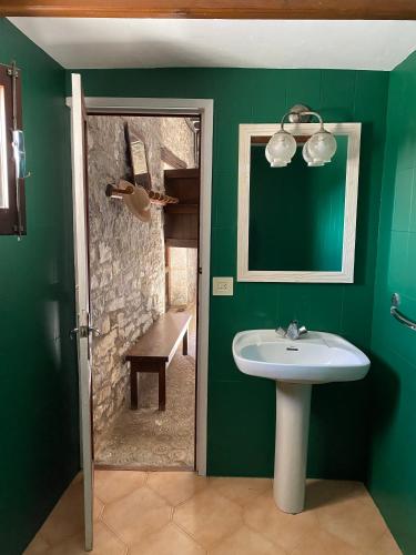 a green bathroom with a sink and a bench at Masía La Perera in Morella