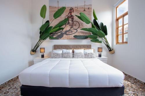 une chambre avec un lit blanc avec un tableau sur le mur dans l'établissement AmazINN Places Boutique Casa Arias, à Panama City