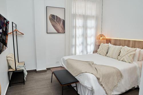 a white bedroom with a bed and a chair at AmazINN Places Rooftop and Design Pool III in Panama City
