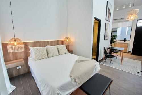 Un dormitorio con una gran cama blanca y una mesa en AmazINN Places Rooftop and Design Pool III en Panamá