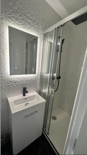 une salle de bain blanche avec un lavabo et une douche dans l'établissement Appartement F2 meublé - tout équipé - Tv netflix - 4 personnes, à Lisieux