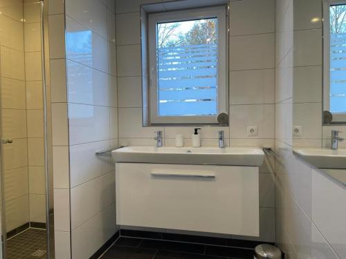 biała łazienka z umywalką i oknem w obiekcie Haus Else w mieście Schüttorf