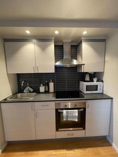 een keuken met witte kasten en een fornuis met oven bij Revtind - Modern apartment with free parking in Narvik
