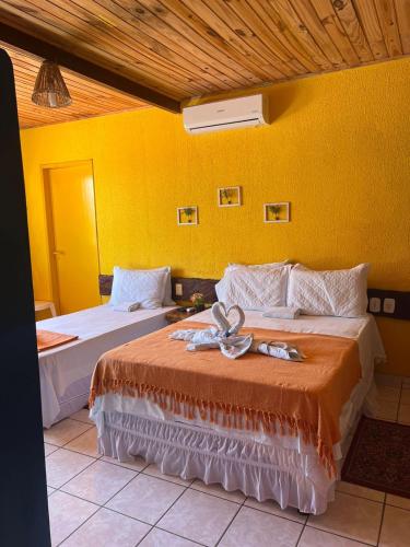 two beds in a room with a yellow wall at Pousada Don Robledo in São Miguel dos Milagres