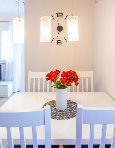 a dining room table with two chairs and a vase with red flowers at Hvar De Luxe Apartments in Hvar